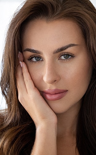 Woman in oversized white shirt, posing gracefully.