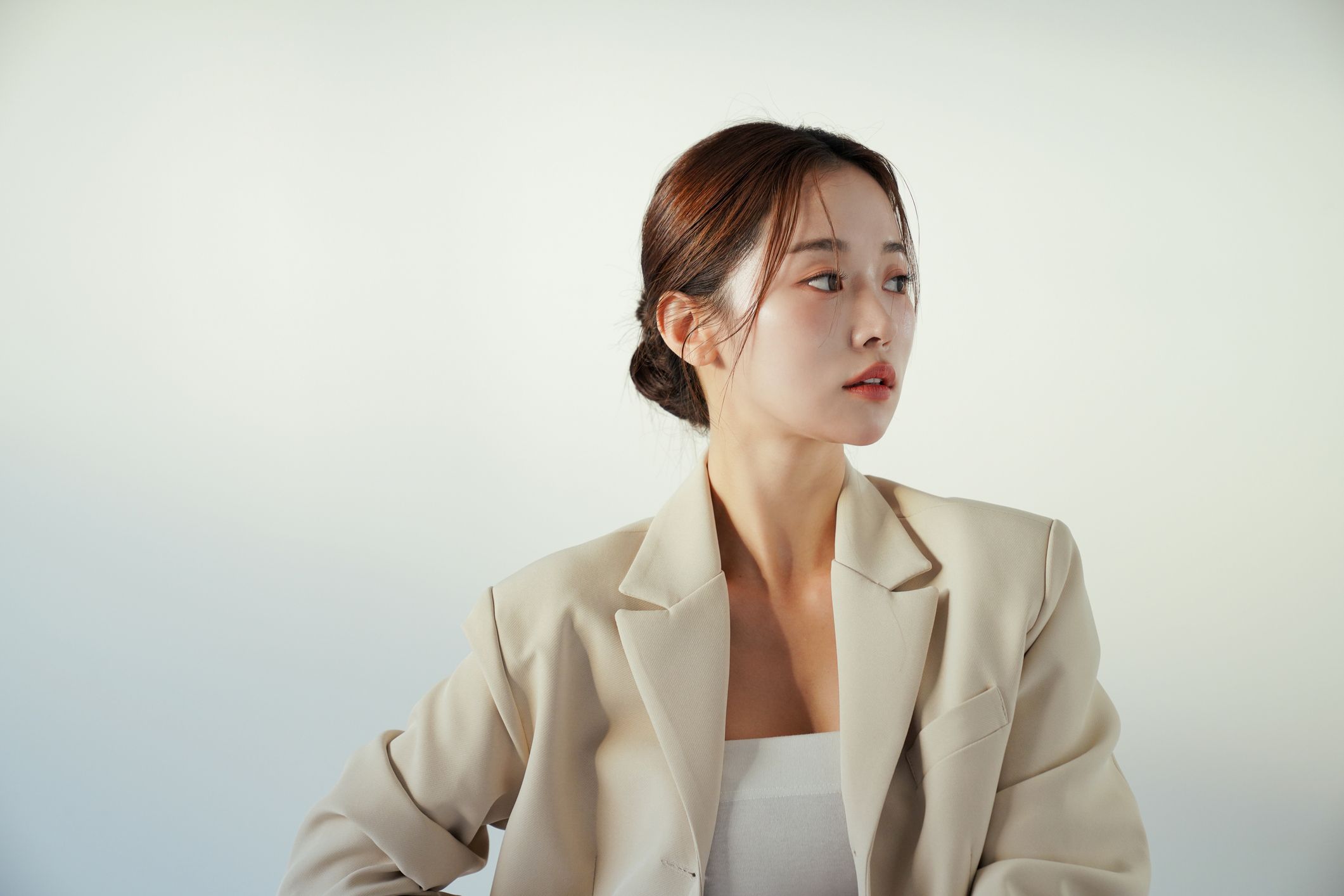 Woman in light blazer against soft background.
